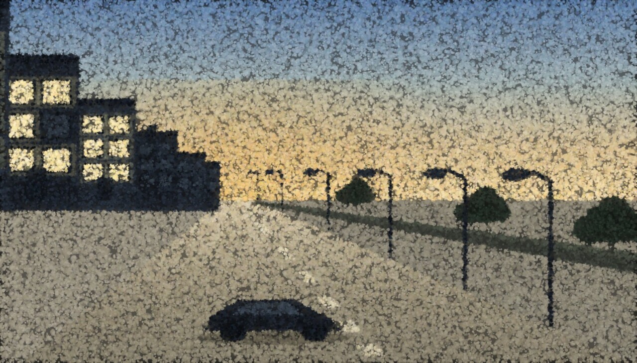 A street at dusk where only the nearest flats have lit windows and everything beyond stands dark against the sky.