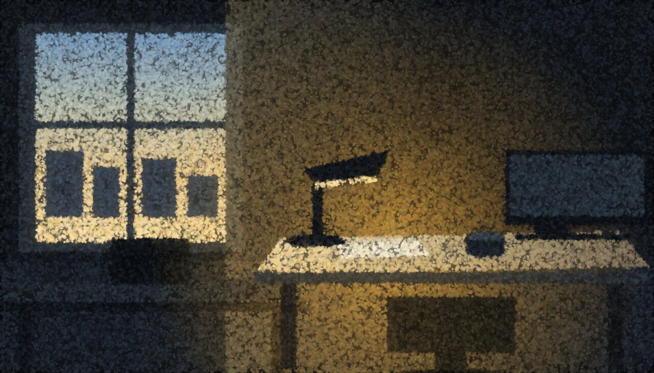 A dark open-plan office at dusk with a window on one side and a single desk still lit by a lamp.