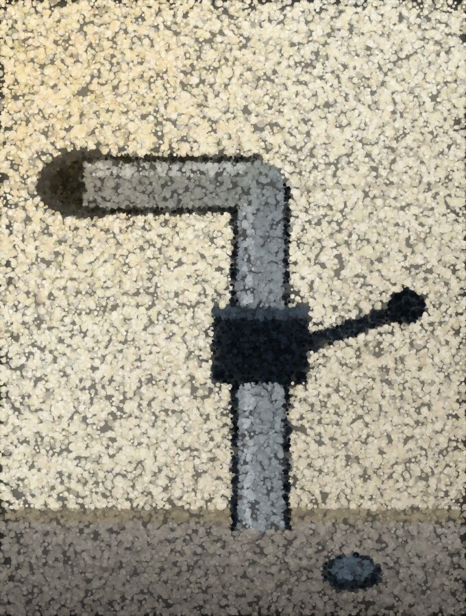 A supply pipe coming through a wall to a stop valve, dull grey with a magnet lying on the floor below.