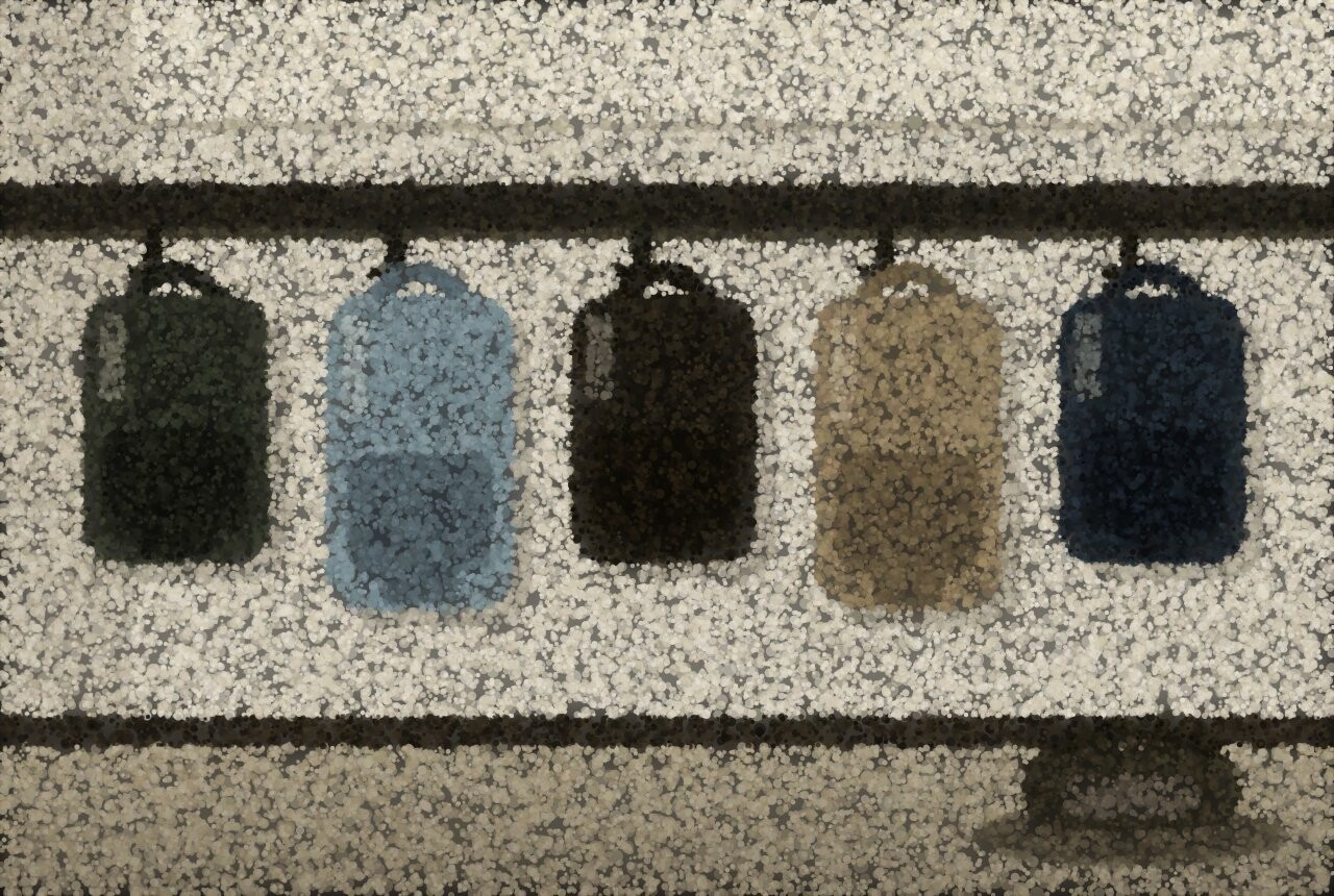 A row of hooks along a school corridor wall with bags hanging from them and one left on the floor.