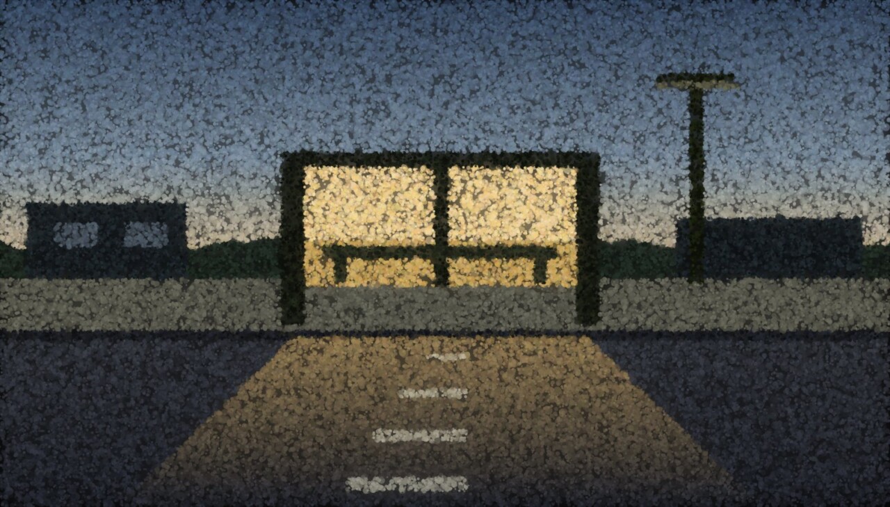 A bus shelter lit from inside beside an empty road at dusk, its light spilling across the wet tarmac.