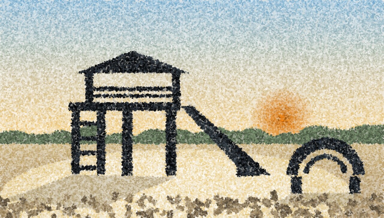 A play tower with a gabled roof, a ladder and a slide standing on pale surfacing, a climbing arch to one side, low sun behind the trees.