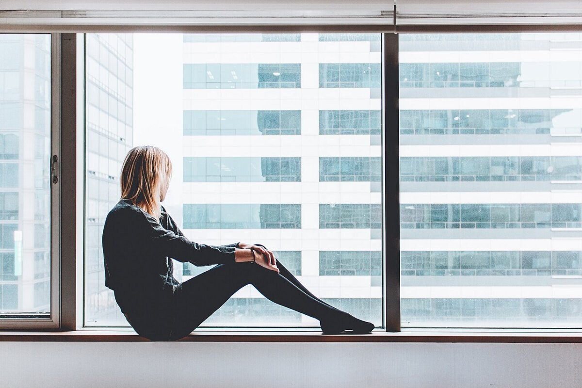 A woman sitting by a large window
