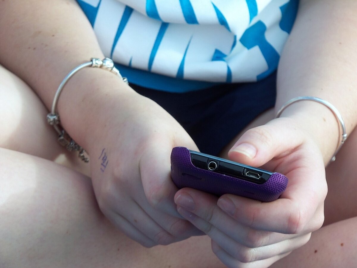 A teenager texting on a smartphone