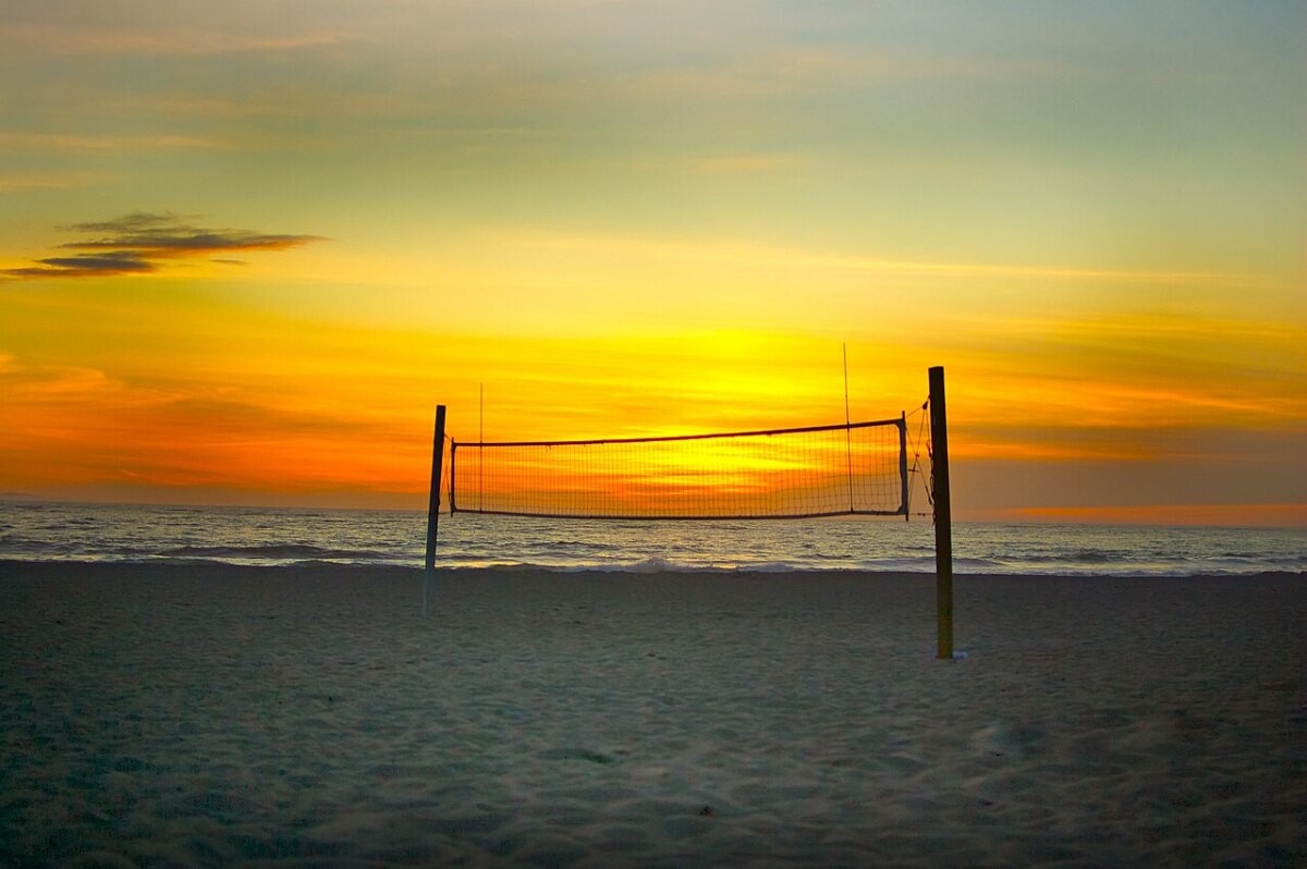 A volleyball net on a desert beach at sunset