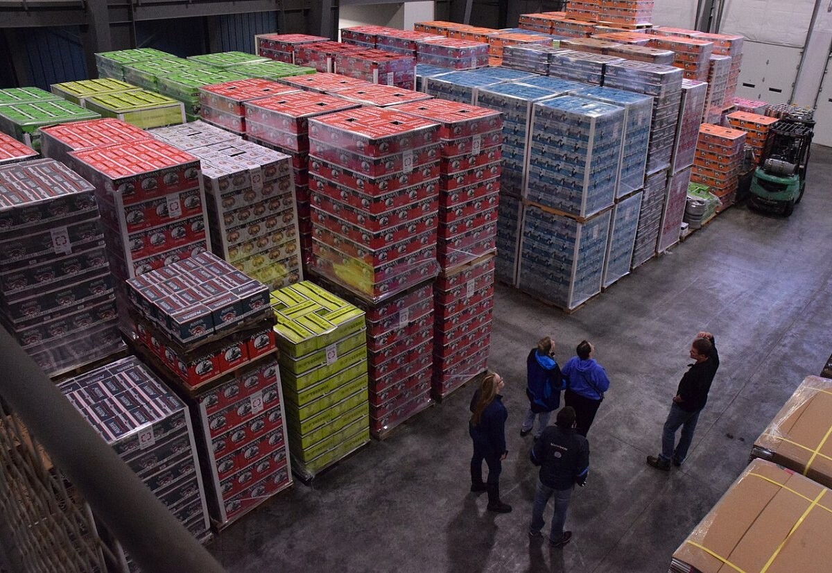 Workers handling pallets in a brewery warehouse