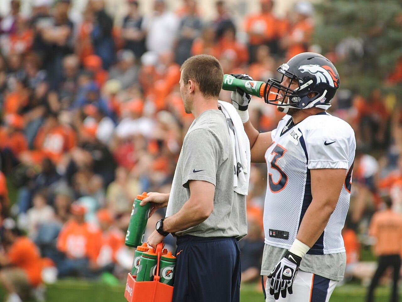 An NFL offensive lineman drinking water during a training camp practice