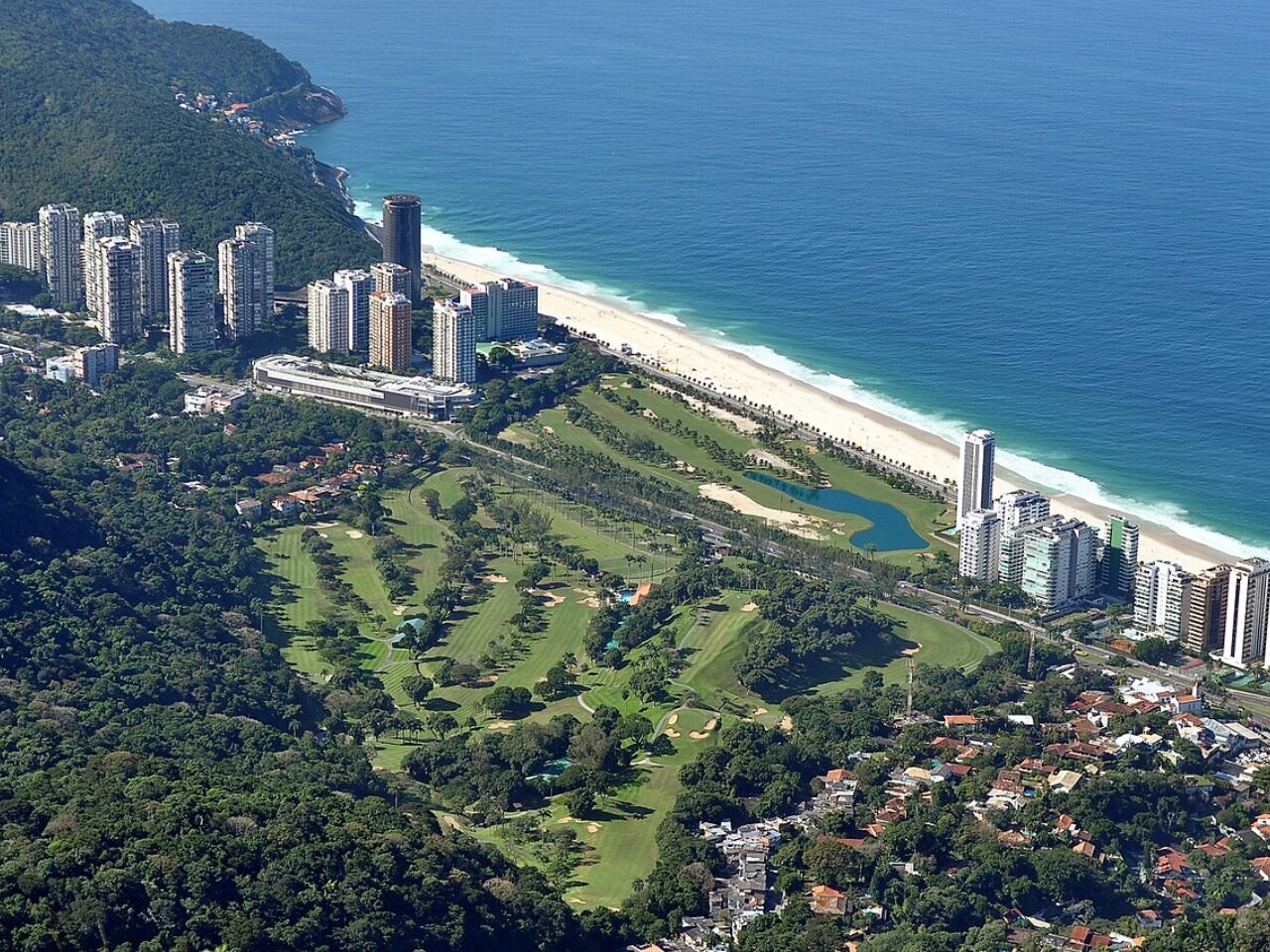 Aerial view of a seaside golf course with apartment towers along its edge