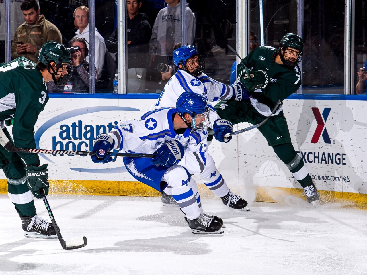 College ice hockey players battling for the puck along the boards
