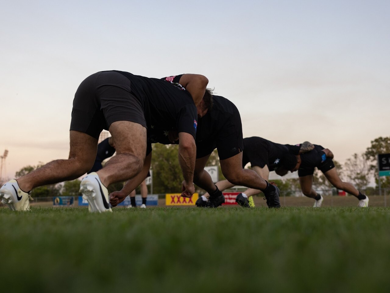 Rugby players bound together practising a scrum on a grass pitch