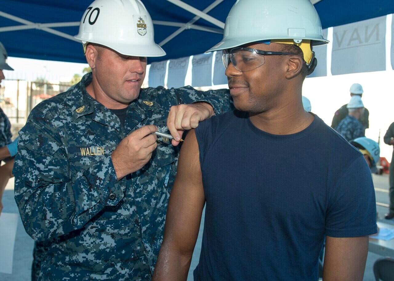 A medic giving a vaccine injection in a man&rsquo;s upper arm