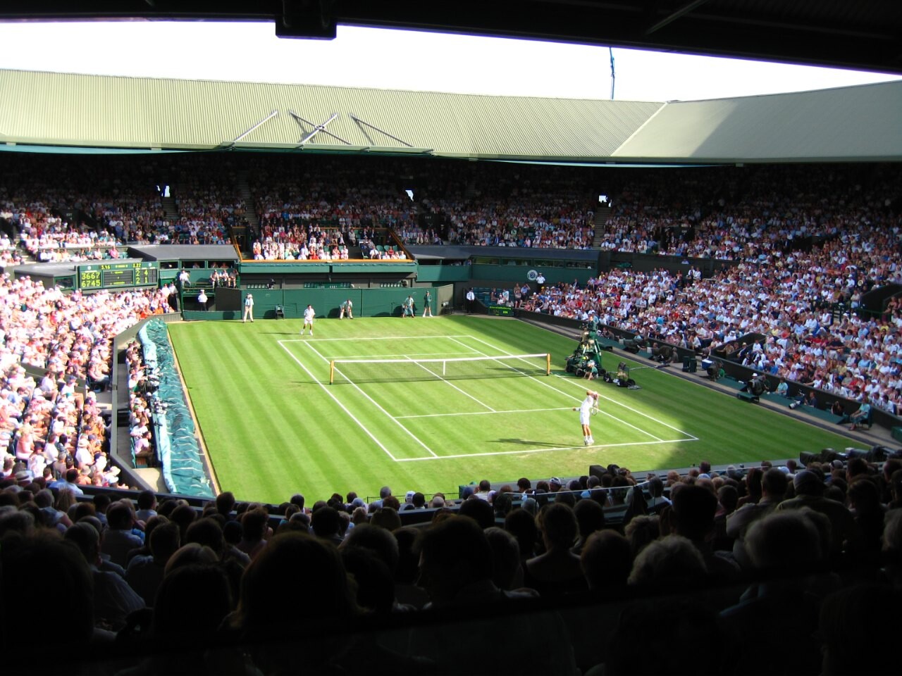 A grass-court match on Centre Court at Wimbledon seen from the stands