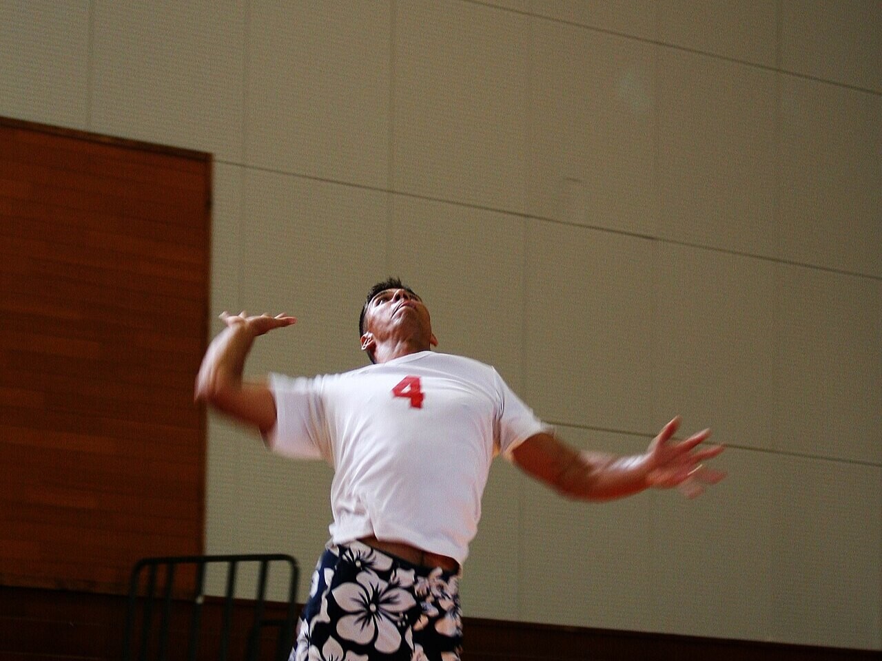 A volleyball player leaping into a jump serve in an indoor gym