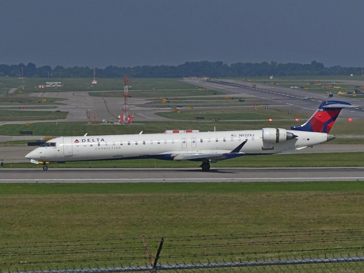 A white regional jet with its thrust reversers deployed on landing