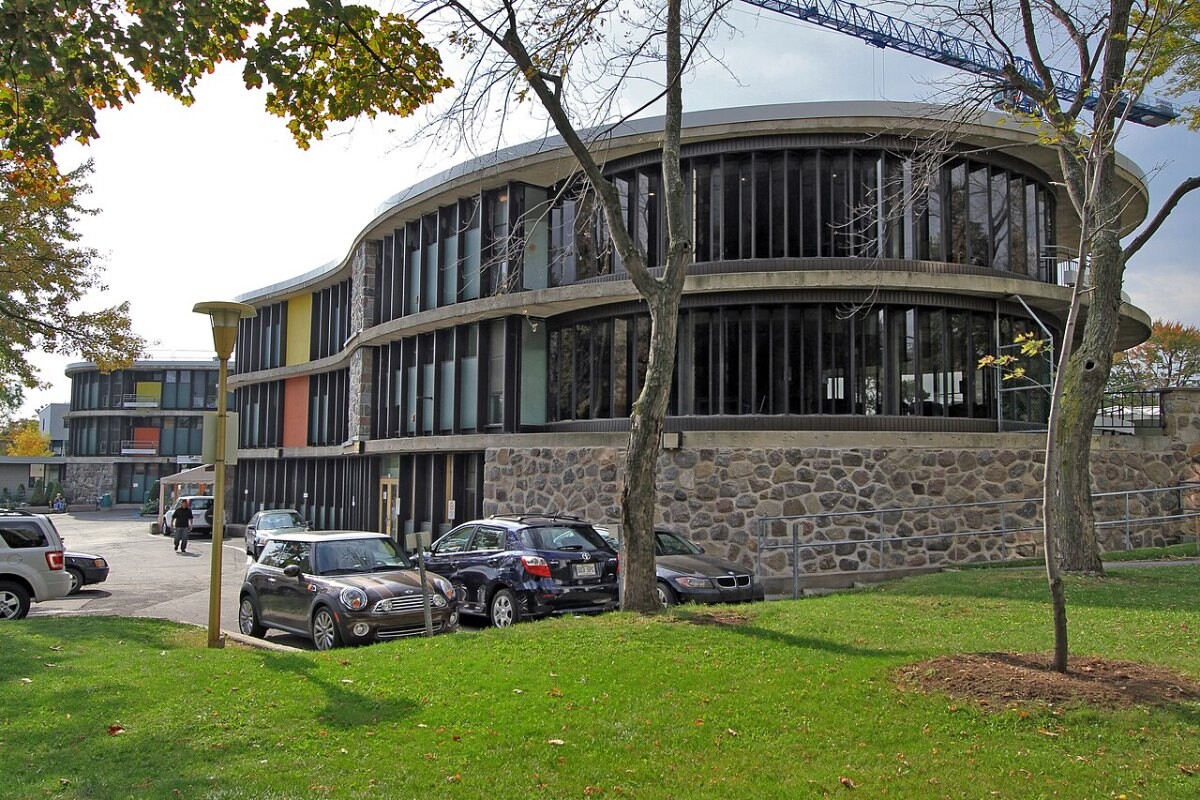 A brick hospital building beside a river path in Montreal