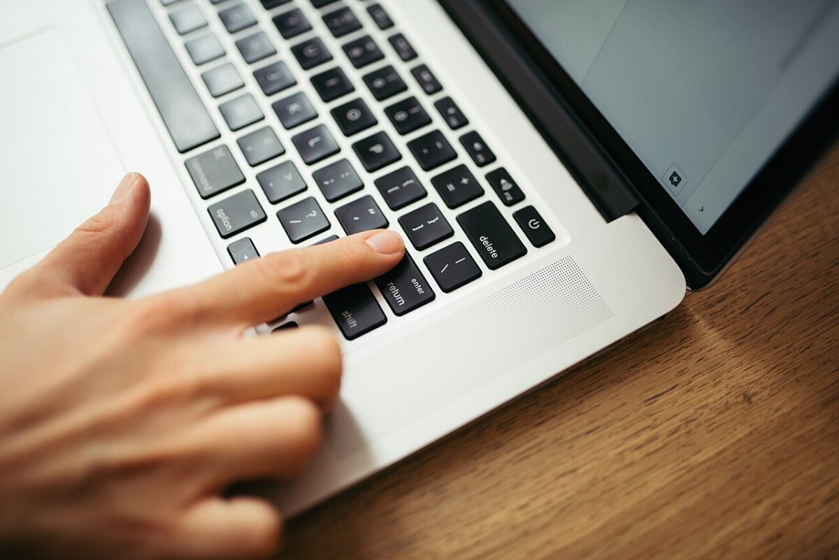 A hand pressing keys on a laptop keyboard