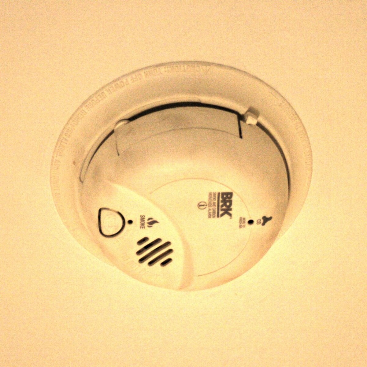 A white smoke detector on a ceiling