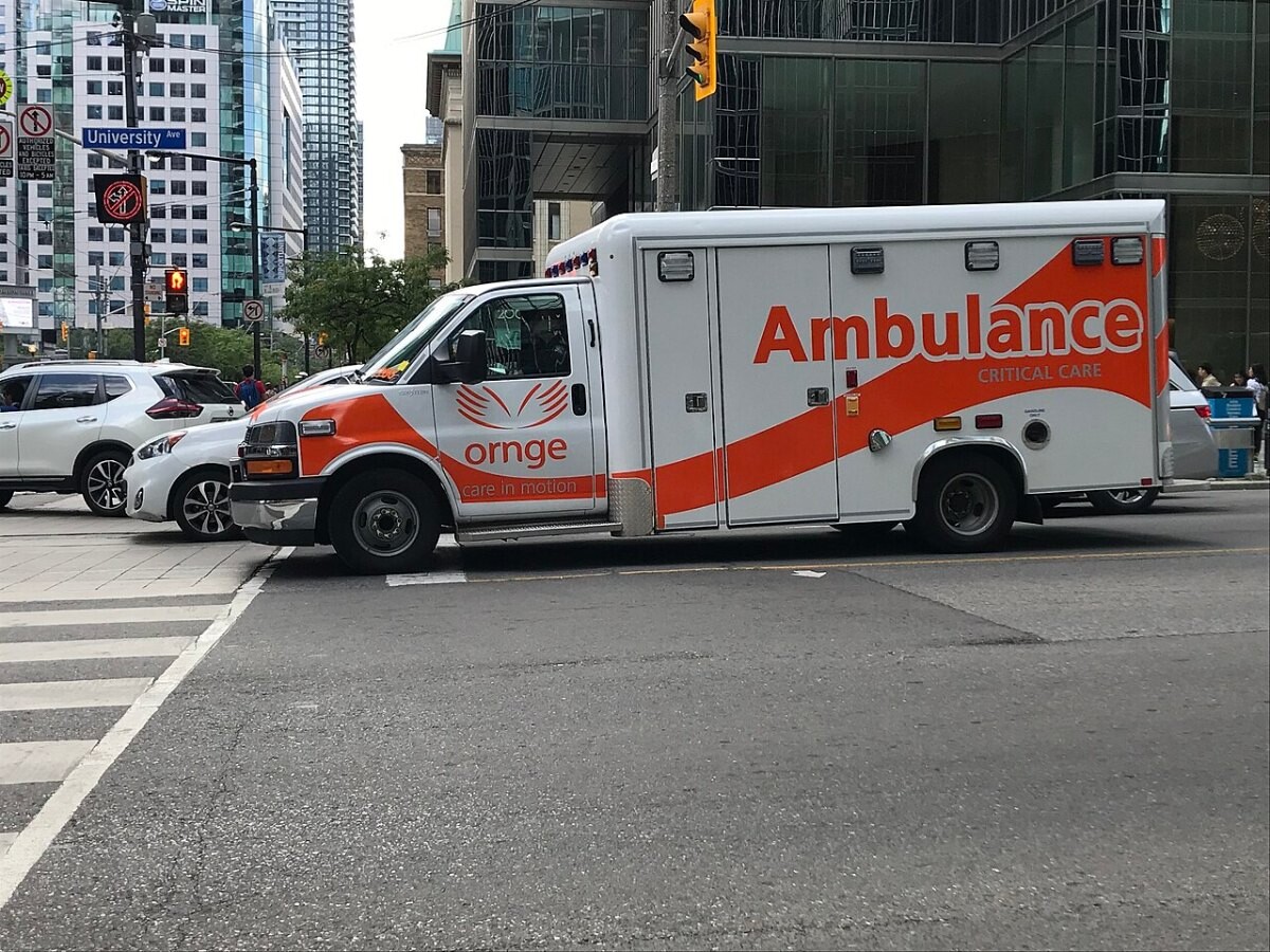 An orange and white critical care ambulance at a city intersection