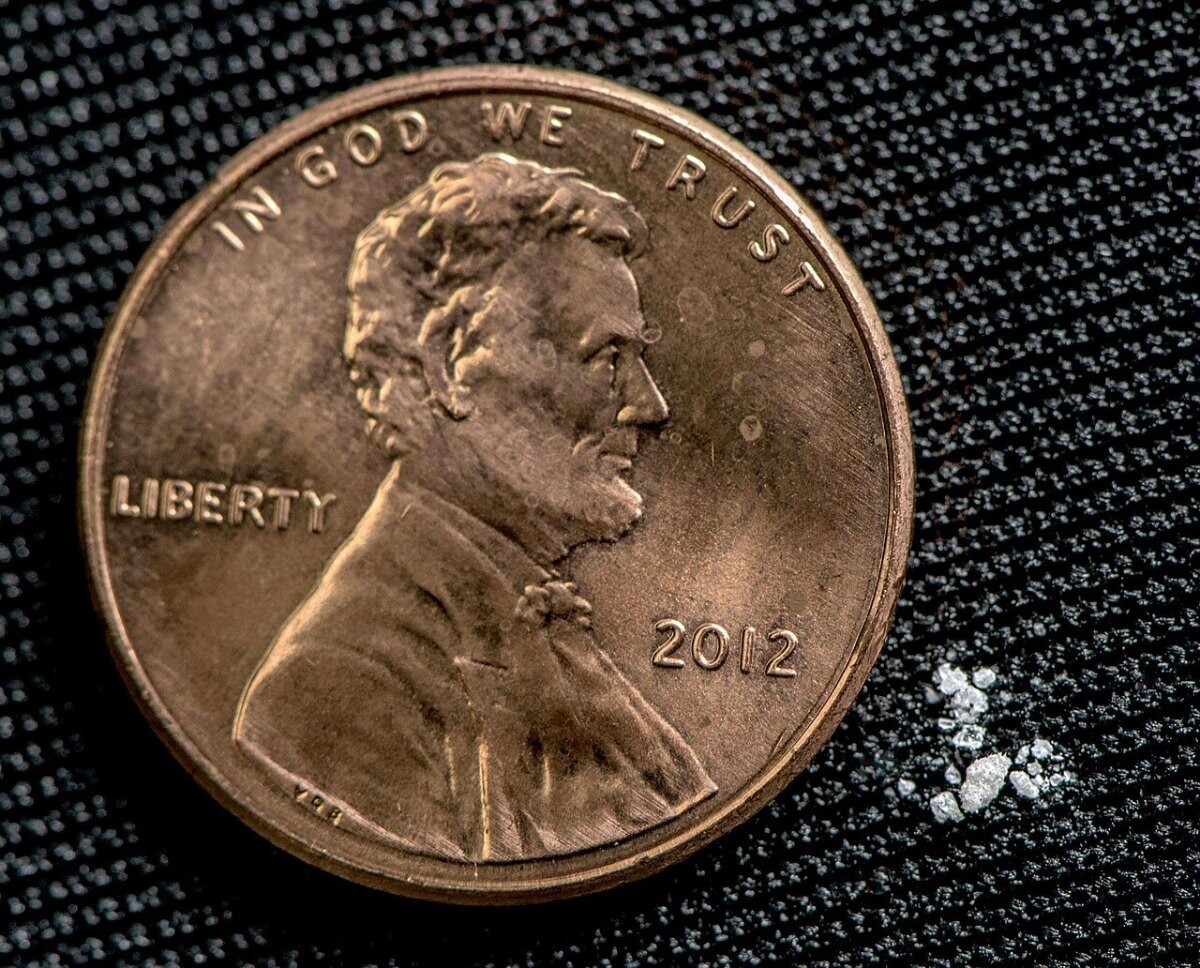 A tiny amount of white powder next to a coin