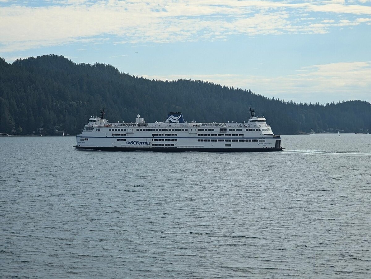 A large white and blue car ferry leaving a terminal