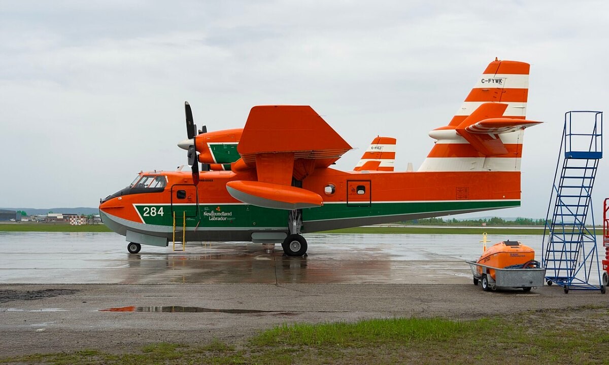 A yellow and red water bomber aircraft parked on an airfield