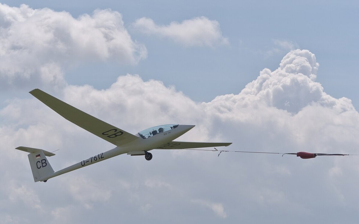 A glider climbing away on a winch launch at a grass airfield