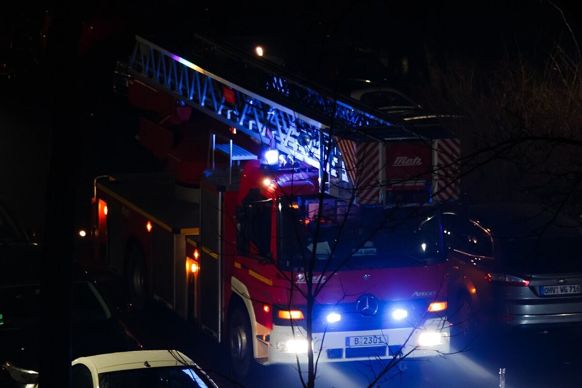 A Berlin fire brigade turntable ladder truck on a city street at night