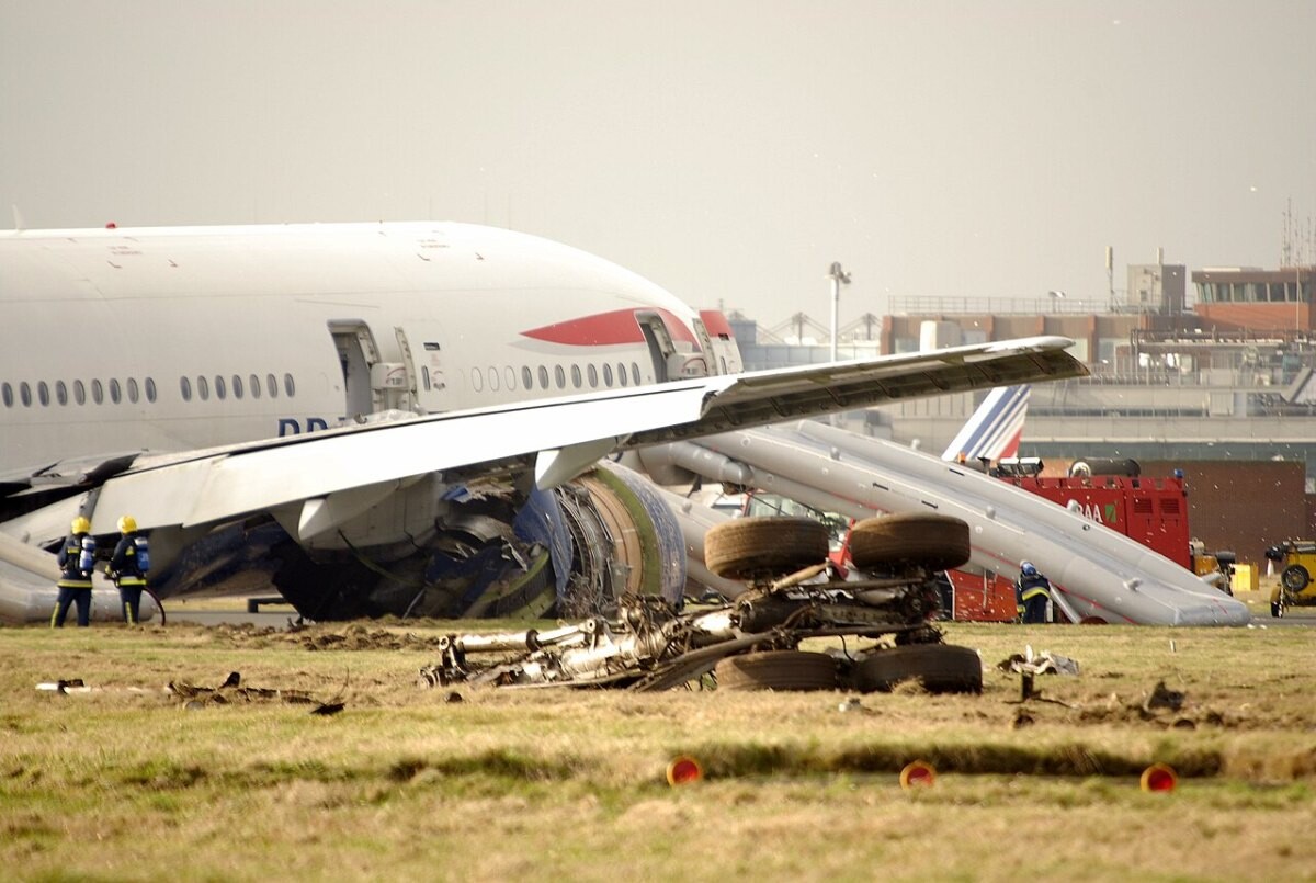 A damaged airliner resting on the grass short of a runway