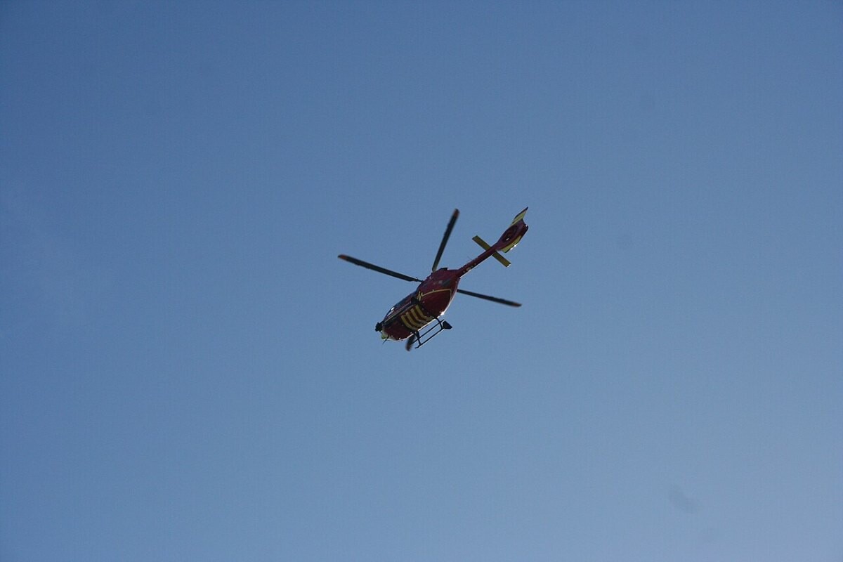 A red air ambulance helicopter flying against a blue sky
