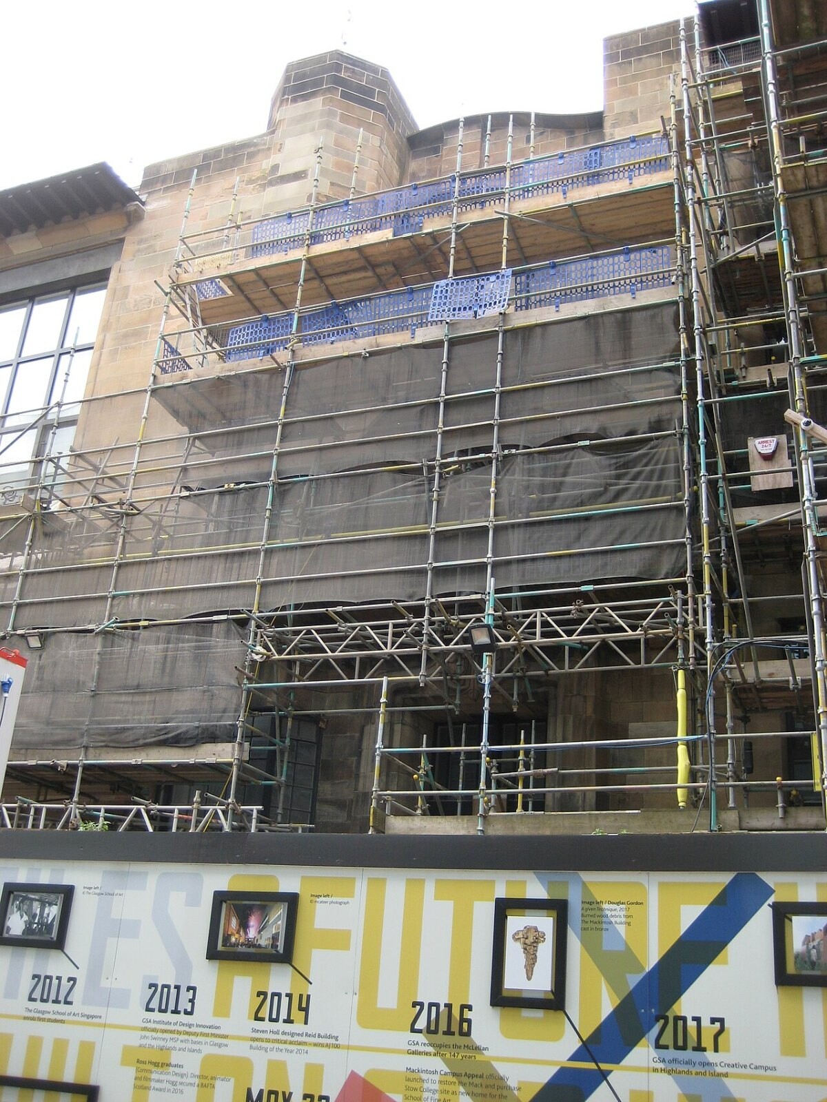 A historic art school building wrapped in scaffolding