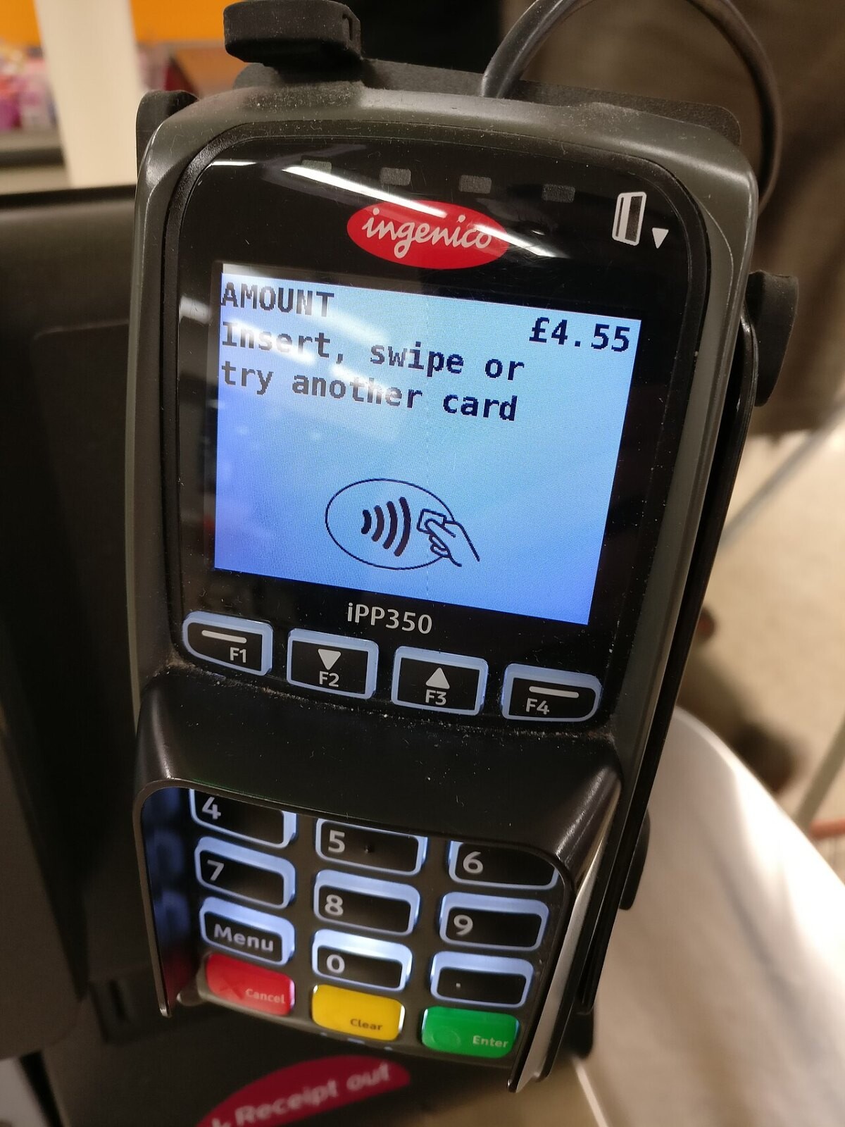 A handheld card payment terminal showing a contactless prompt