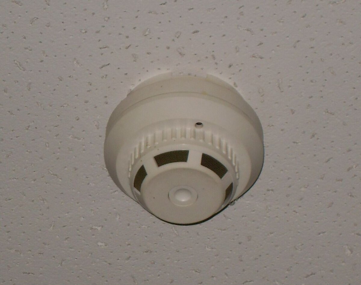 Round white smoke detector on a ceiling