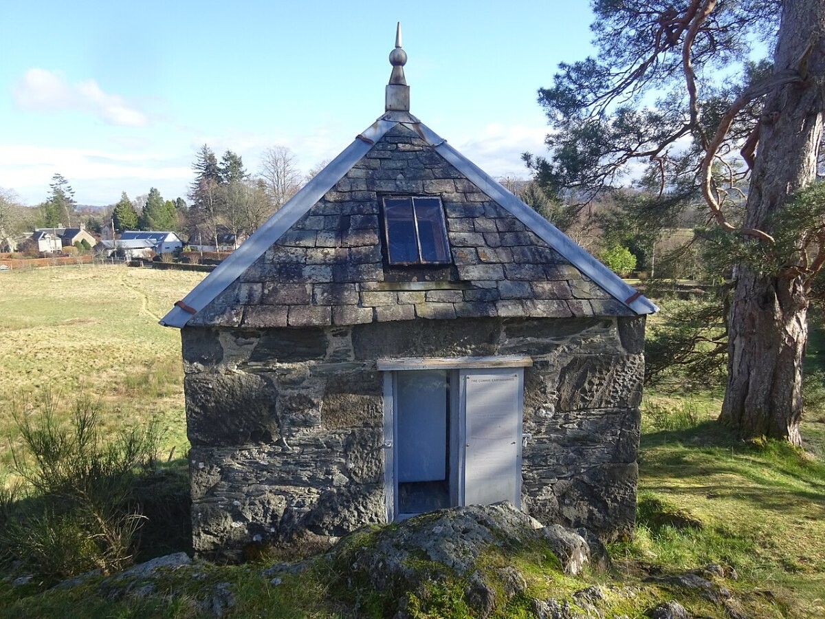Small stone hut with a pitched roof on a grassy slope
