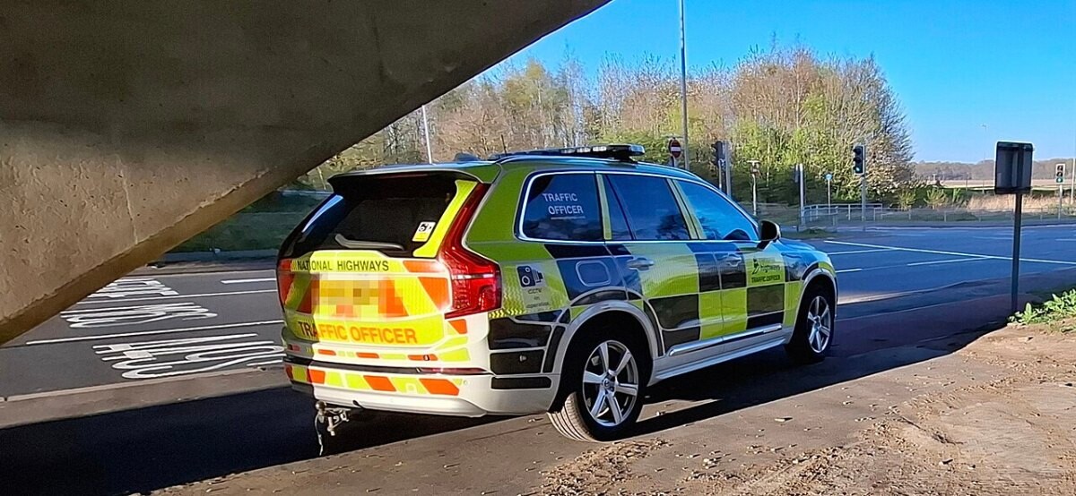 A yellow-and-black chequered traffic officer SUV parked by a road