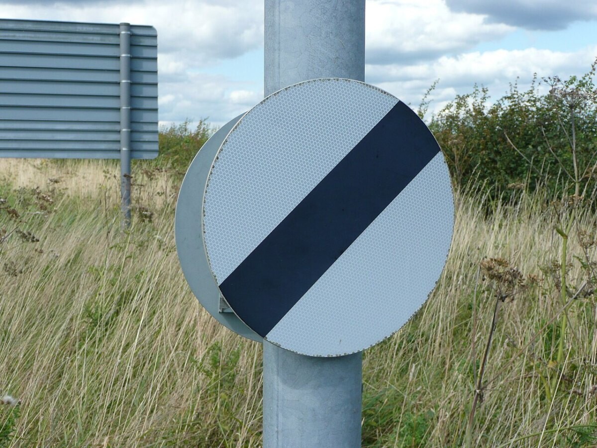 A white circular road sign with a black diagonal stripe