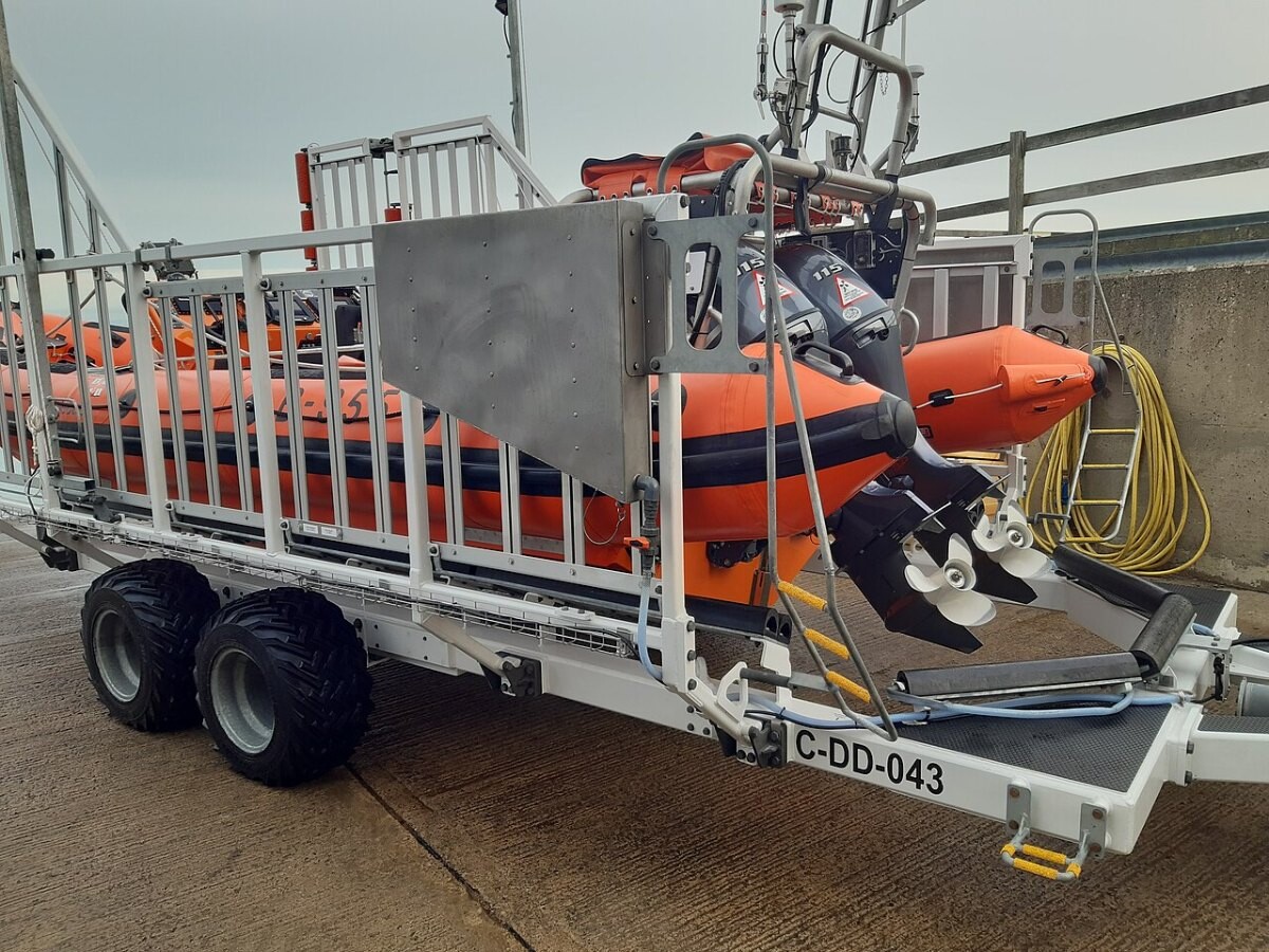 An orange RNLI inflatable lifeboat on its launch trailer on a slipway