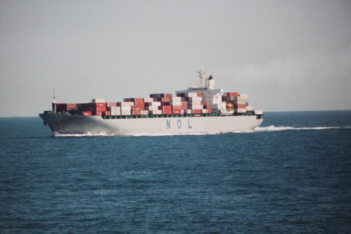 A large container ship at sea under grey skies