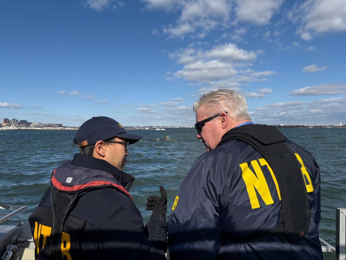 An NTSB board member talking with an engineer at a riverside recovery site