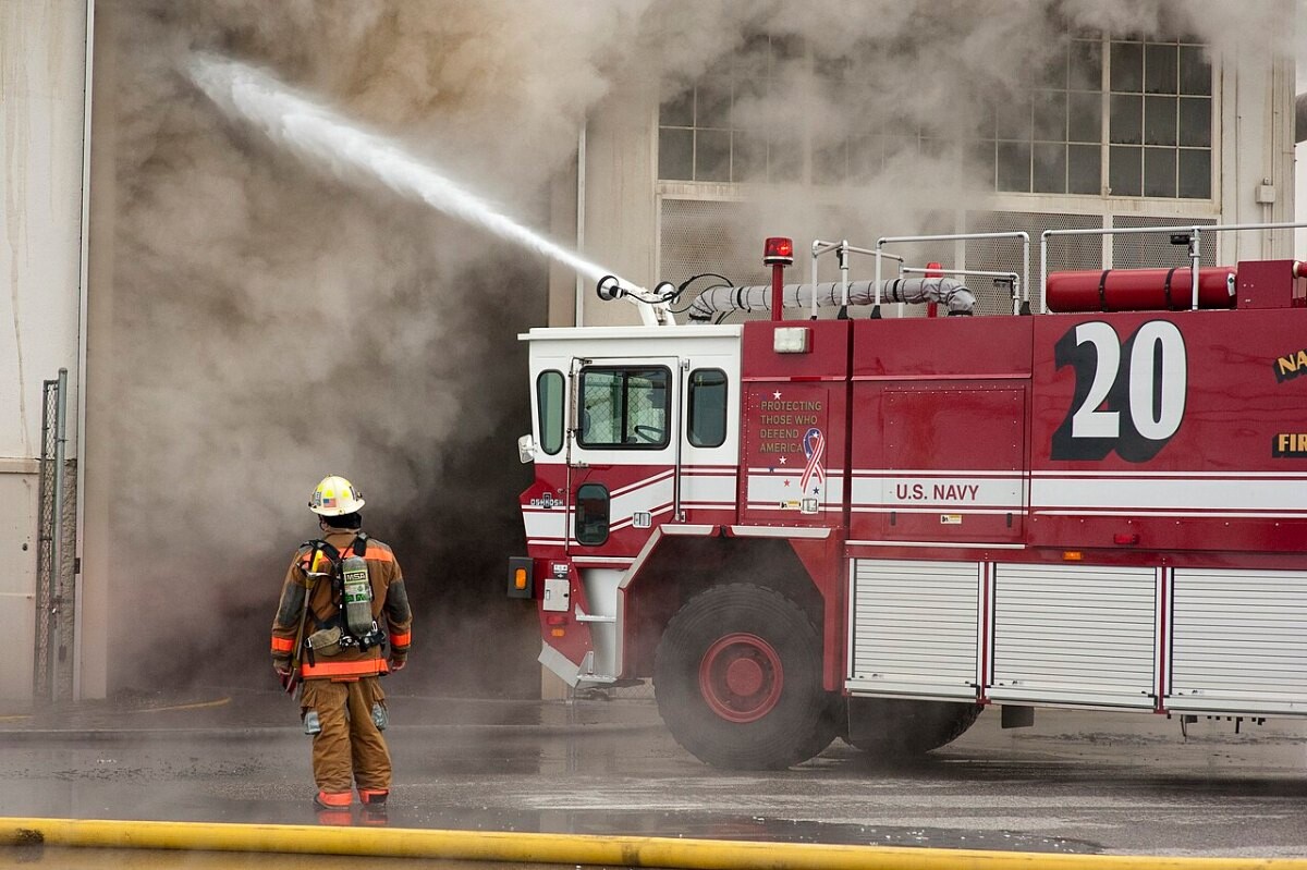 Firefighters spraying water on a smoking warehouse
