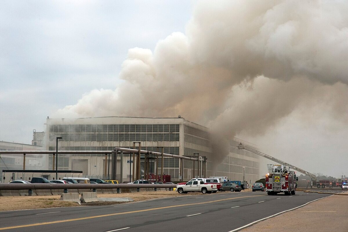 Fire appliance and hoses outside a warehouse wrapped in smoke