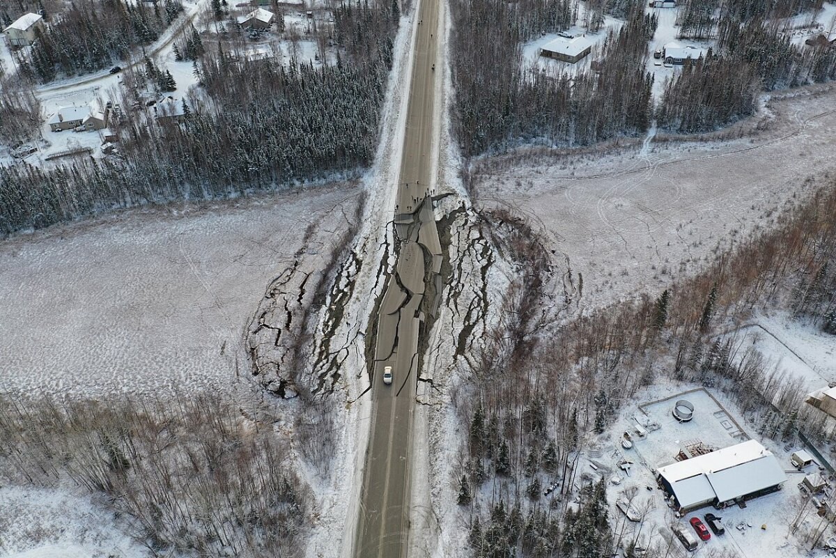 A rural road with a deep crack and slumped asphalt after an earthquake